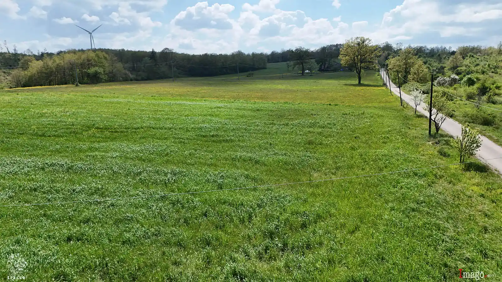Veduta aerea nei pressi di Santa Croce del Sannio: in primo piano, a sinistra, un’ampia area agricola segue il margine del vecchio tracciato del Regio Tratturo Pescasseroli-Candela, riconoscibile sulla destra lungo il corridoio erboso che costeggia la strada rurale.