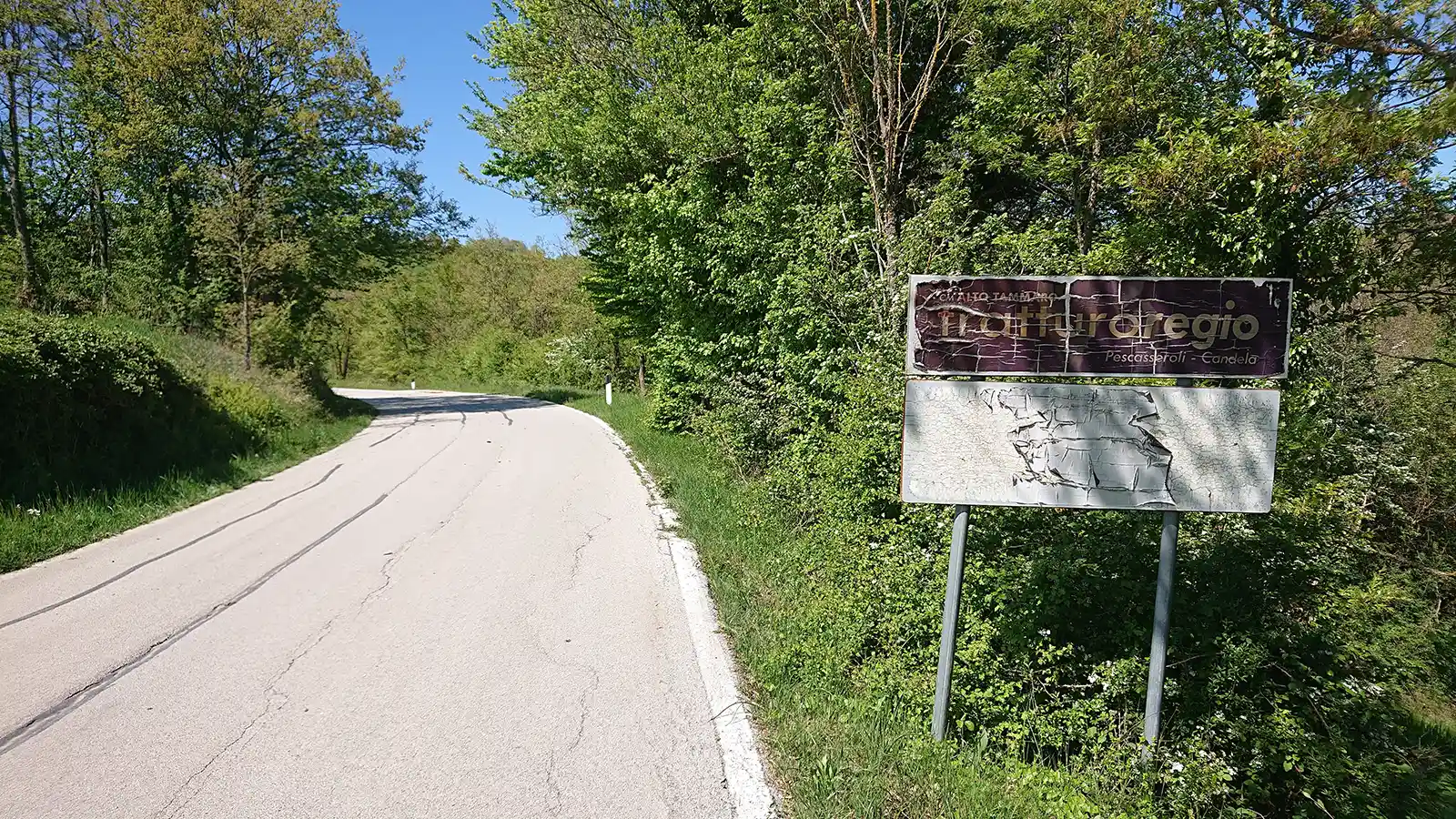 Vecchio cartello stradale posto lungo la SP 54 nei pressi di Santa Croce del Sannio che segnala l’attraversamento del Regio Tratturo Pescasseroli-Candela. Il segnale, visibilmente deteriorato dal tempo, si trova sul margine della strada immerso nella vegetazione del paesaggio rurale sannita.
